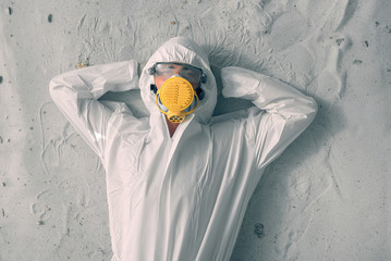 A man in white protective uniform, respirator and plastic transparent glasses.