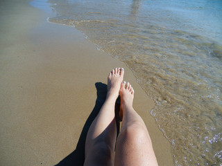 High angle view og  woman feet  relaxing on seashore  in Greece during summer