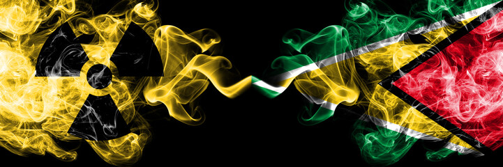 Guyana, Guyanese vs nuclear smoky mystic flags placed side by side. Thick colored silky smokes combination of Guyana, Guyanese flag and radioactive sign.