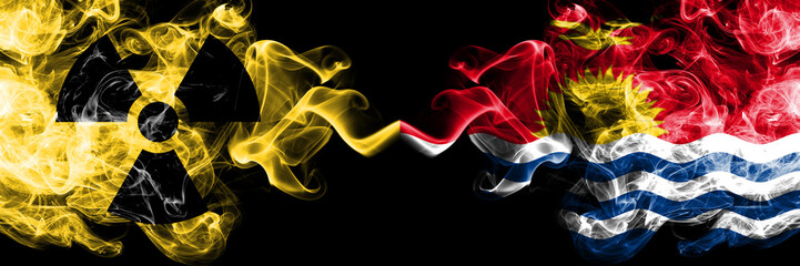 Kiribati vs nuclear smoky mystic flags placed side by side. Thick colored silky smokes combination of Kiribati flag and radioactive sign.