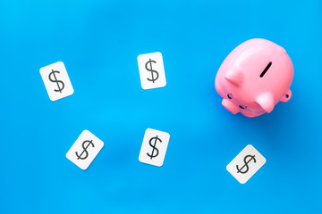 Moneybox in shape of pig and dollar sign for business budget on blue background top view