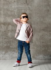 Obraz premium Image of cheerful excited little boy child standing isolated over concrete wall.