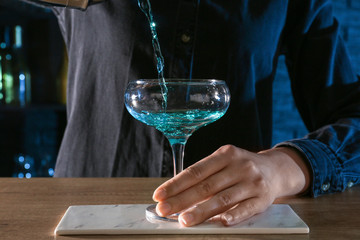 Barkeeper preparing Blue Lagoon cocktail at table in bar