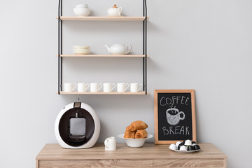 Modern coffee machine and croissants on kitchen table