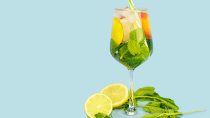 Glass of refreshing drink on blue background. Copy space. 16:9. Summer lemonade with nectarine, mint, lime and lemon.