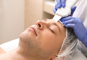 Fototapeta na wymiar Handsome man undergoing procedure of facial peeling in beauty salon