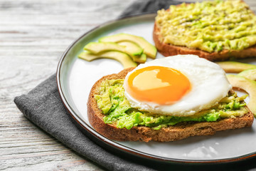 Plate with tasty avocado toasts on table, closeup