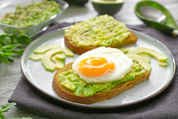 Fototapeta na wymiar Plate with tasty avocado toasts on table