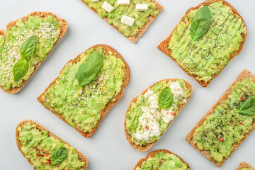 Different tasty avocado toasts on grey background