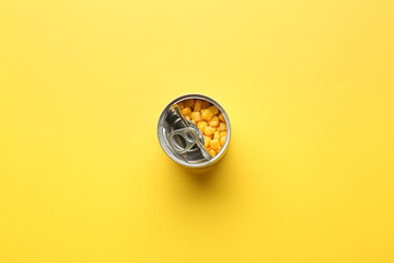 Tin can with corn on color background