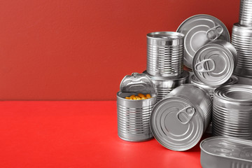 Tin cans with food on color background