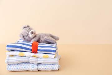 Stack of baby clothes on color background