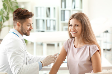 Doctor vaccinating young woman in clinic