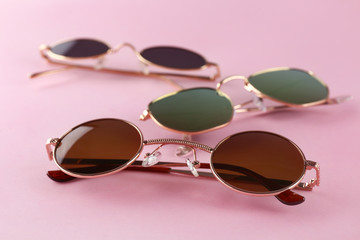Different stylish sunglasses on color background