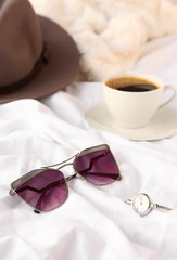 Stylish sunglasses with wrist watch on bed
