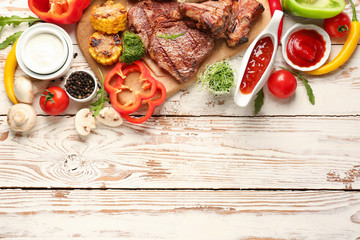 Tasty grilled meat vegetables on white wooden background
