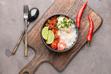 Bowl with tasty chili con carne and rice on table