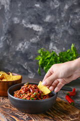 Woman eating tasty chili con carne with nachos