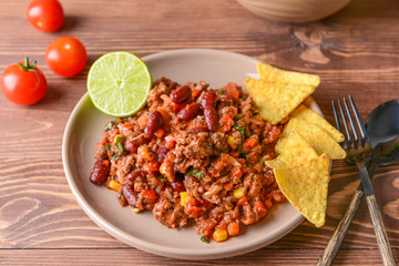 Plate with tasty chili con carne on wooden table