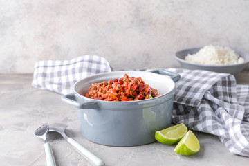 Pot with tasty chili con carne on grey table