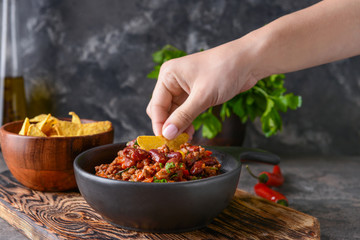 Woman eating tasty chili con carne with nachos