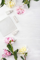 Beautiful peony flowers and cosmetics on light background