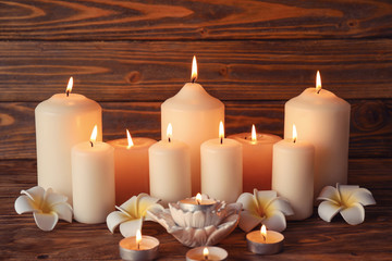 Beautiful spa composition with burning candles and flowers on wooden background