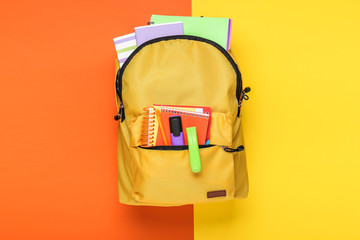 Backpack with school supplies on color background