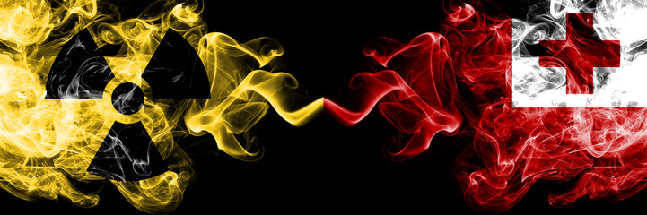 Tonga, Tongan vs nuclear smoky mystic flags placed side by side. Thick colored silky smokes combination of Tonga, Tongan flag and radioactive sign.