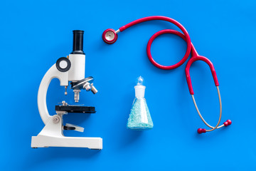 Medical research with microscope, stethoscope, test tube on blue background top view