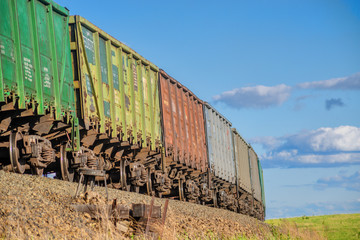 Obraz premium Rural summer landscape with freight train passing field at sunny day 