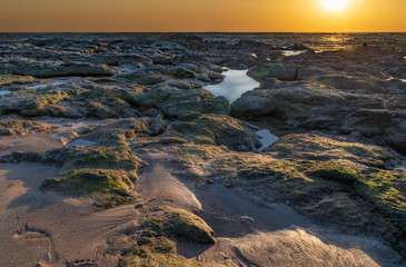 Sunset over the ocean horizon with reflections and sun flares
