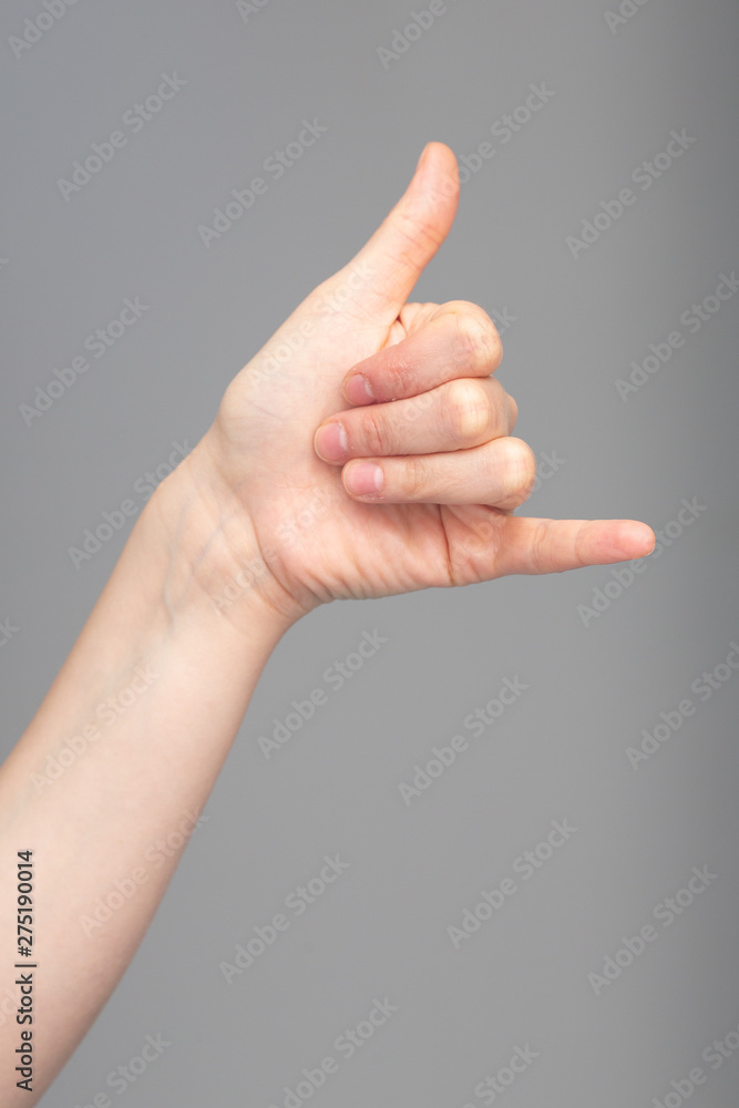 Wall mural hand and arm of a caucasian person is seen close-up and isolated against a grey background. giving t