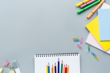 School supplies stationery, colour pencils, clips, paper on gray background, back to school concept with copy space for text, overhead, modern elementary education. flat lay, top view, mockup