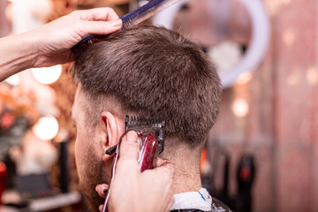Haircut closeup. Hands holding a hair clipper. Barber, style creation, beauty. Beauty saloon.