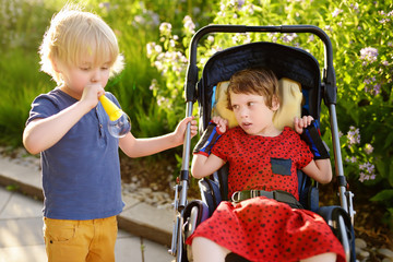 Little boy and a disabled girl playing together in the summer park. Child cerebral palsy. Family...