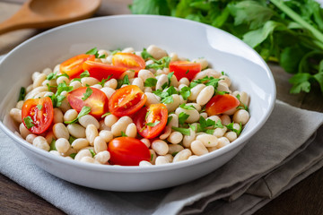 White bean salad with cherry tomatoes and parsley in bowl