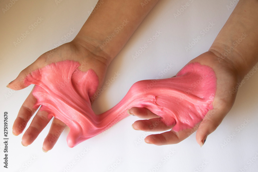 Wall mural Hands Manipulating Pink Slime Hands pulling, twisting, squeezing slime. Slime resembles bubble gum. Gooey, stretchy, flexible, satisfying, tactile experience. Gross texture. Childhood fun. Innocent pl