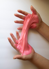 Hands Manipulating Pink Slime Hands pulling, twisting, squeezing slime. Slime resembles bubble gum. Gooey, stretchy, flexible, satisfying, tactile experience. Gross texture. Childhood fun. Innocent pl