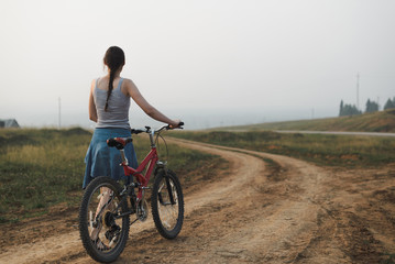 white caucasian young woman in casual clothing walking with bike on village road, view from back in full body size, lifestyles stock photo image © anastasiia agafonova