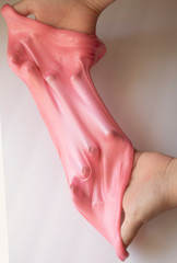 Hands Manipulating Pink Slime Hands pulling, twisting, squeezing slime. Slime resembles bubble gum. Gooey, stretchy, flexible, satisfying, tactile experience. Gross texture. Childhood fun. Innocent pl