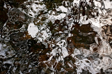 Brown, Black and White Ripples on a River Detail. Abstract background. Water closeup. Wet pattern. Beautiful and unique. Peaceful nature.