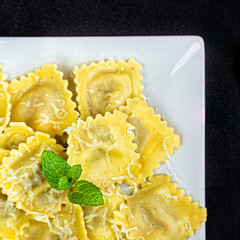 Fresh raviolli on a white plate  over  dark background, top view.  Italian Raviolli close up.