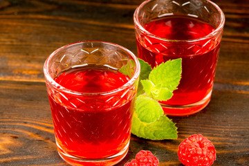 red nonalcoholic raspberry juice with mint on wooden table