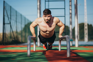 Fototapeta premium man performing push-ups on some calisthenics bars