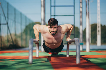 man performing push ups on some calisthenics bars