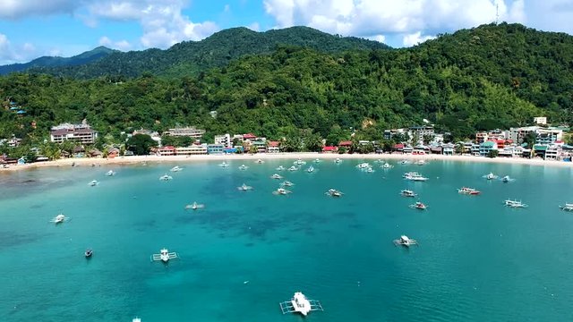 Aerial reveal of boats docked in the sea by El Nido Town, Palawan, Philippines