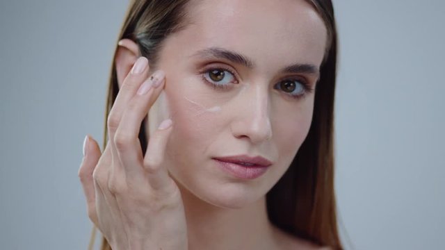 Young woman uses creams for the beauty of her face daytime and night-time concept for fresh and moisturized skin beautiful closeup cosmetic face happy health healthy isolated model slow motion