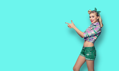 woman, dressed in pin-up style, showing something or copyspace, over blue green color background