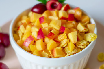 Healthy breakfast with cornflakes and pieces of fruit, cherries on a white background